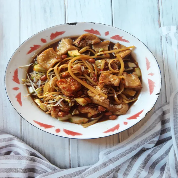 Sajikan mie, tahu, timun dan siram kuah. Lalu taburkan bawang goreng, kacang goreng dan seledri.
