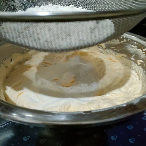 Masukkan tepung terigu dan susu bubuk sambil ayak dan diaduk hingga rata.