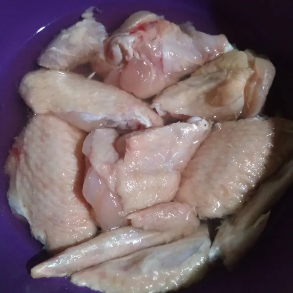Potong dan cuci bersih sayap ayam, lalu marinasi sebentar dengan garam.