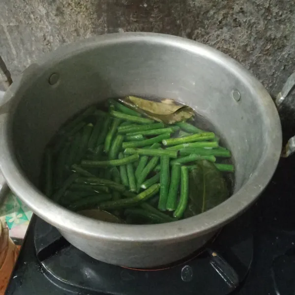 Rebus air hingga mendidih, masukkan kacang panjang, lengkuas, dan daun salam. Rebus hingga kacang setengah matang.