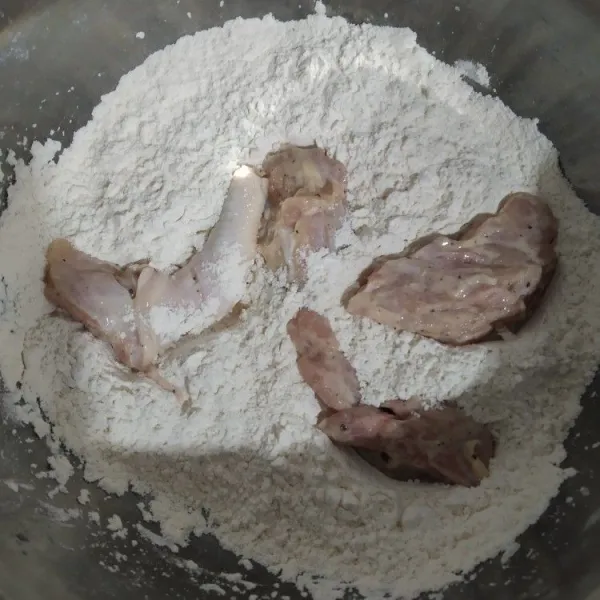 Setelah satu jam keluarkan ayam dari kulkas, lalu masukan beberapa potong ayam ke dalam tepung bumbu aduk-aduk saja jangan diremas.