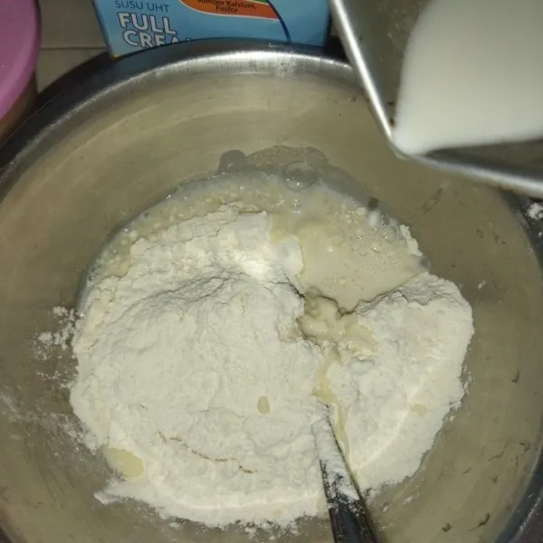 Lalu masukkan tepung terigu dan susu cair hangat, lalu uleni hingga setengah kalis.