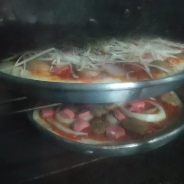 Panggang ke dalam oven yang sudah dipanaskan sebelumnya pada suhu 170°C selama 15 menit. Setelah dipanggang selama 15 menit, beri taburan keju dan panggang kembali. Setelah matang keluarkan pizza, beri saus mayonnaise dan saus tomat. Potong-potong, lalu sajikan.
