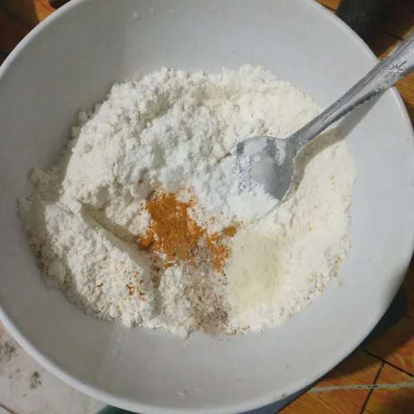 Campurkan tepung terigu, garam, kaldu bubuk, lada bubuk, ketumbar bubuk, bawang putih bubuk dan kunyit bubuk. Aduk rata.