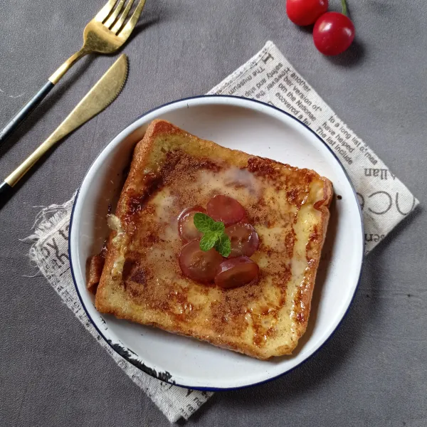 Timpa dengan roti tawar yang satunya lagi, kucuri lagi dengan kental manis dan taburi kayu manis bubuk. Tata juga irisan anggur, sajikan selagi hangat.