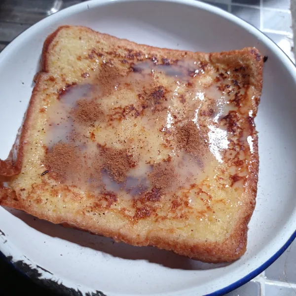 Ambil selembar roti tawar yang sudah matang, kucuri kental manis dan bubuk kayu manis.