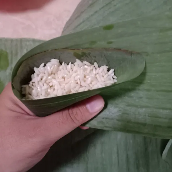 Isi daun dengan beras ketan.