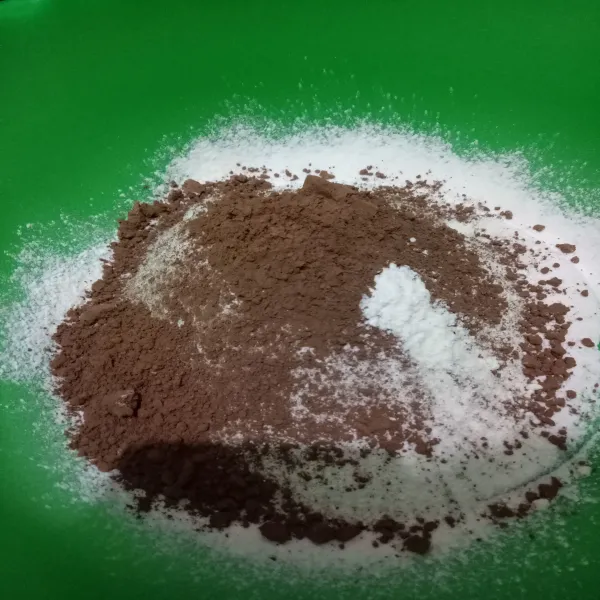 Ayak tepung terigu, gula, baking soda dan baking powder. Tambahkan coklat bubuk. Panaskan juga kukusan yang tutupnya dilapisi kain bersih.