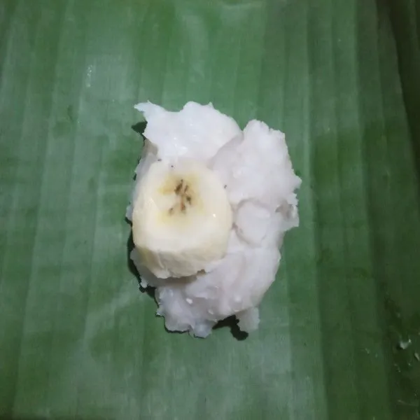 Siapkan daun pisang lalu ambil 1 sdm adonan, masukkan ke dalam daun pisang dan masukkan pisang lalu bungkus dan tusuk dengan lidi lakukan sampai adonan habis.