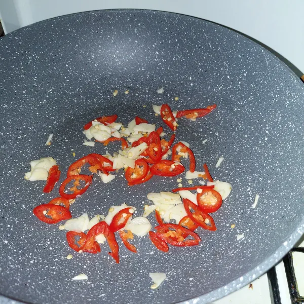 Tumis bawang putih hingga harum, tambahkan cabai merah, lalu masak sambil diaduk.