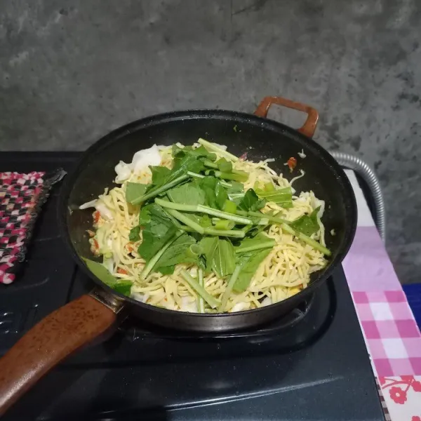 Selanjutnya masukkan mie, sawi, dan daun bawang. Aduk sampai rata dengan bumbu.