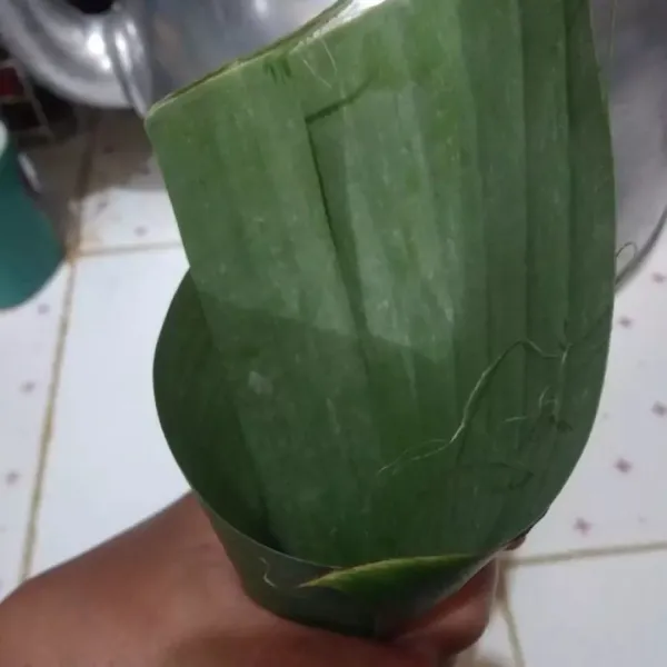 Bentuk daun pisang menyerupai corong. Lalu masukkan beras ketan, tutup rapat dengan tusuk gigi/ lidi.