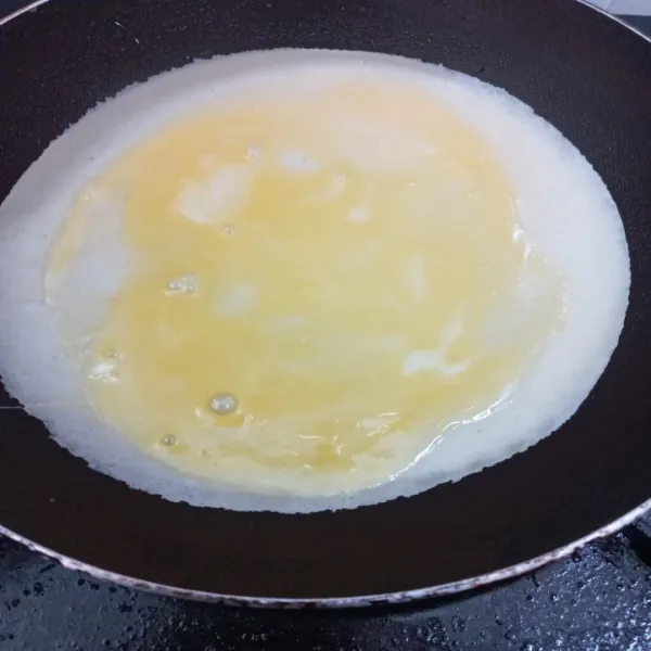 Panaskan teflon, beri sedikit minyak menggunakan tissu, tuang 1 sendok sayur adonan leker lalu beri diatasnya telur kocok.