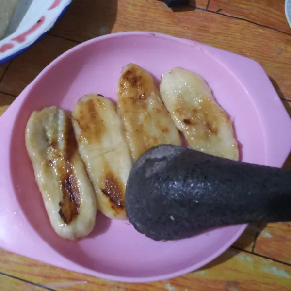 Tata pisang dipiring lalu penyet pisang menggunakan ulekan.