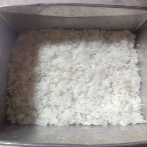 Siapkan loyang ukuran 18 yang di alasi plastik, bagi menjadi 2 bagian beras ketan yang sudahh di kukus. Letakkan di loyang 1 bagian, ratakan.