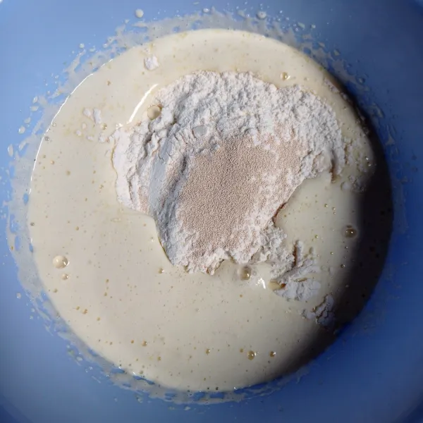 Masukkan tepung terigu, ragi instan, vanili, garam, dan santan, lalu mixer sampai tercampur rata dan licin.