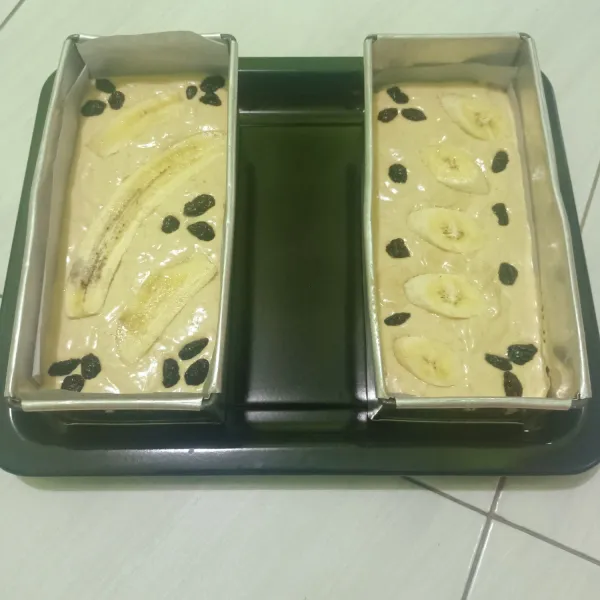 Siapkan loyang lalu olesi dengan margarin/ kertas roti. Tuang adonan ke dalam loyang. Beri toping diatasnya.