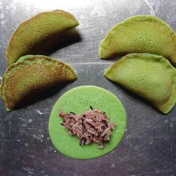 Panaskan teflon. Gunakan api kecil. Tuang adonan 1 sendiok sayur. Biarkan hingga berpori. Setelah permukaan matang, angkat. Beri isian ketan item dan kelapa parut secukupnya. Lipat dan rekatkan.