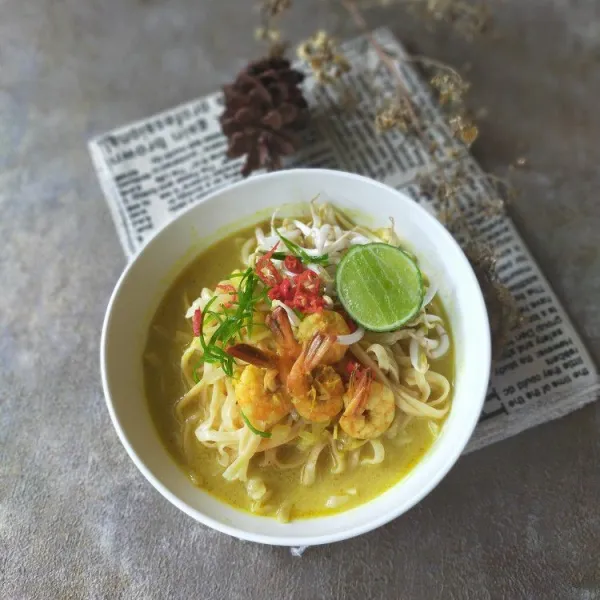 Tata mie kuning di piring saji. Beri kuah kari udang. Beri bahan topping. Sajikan hangat.