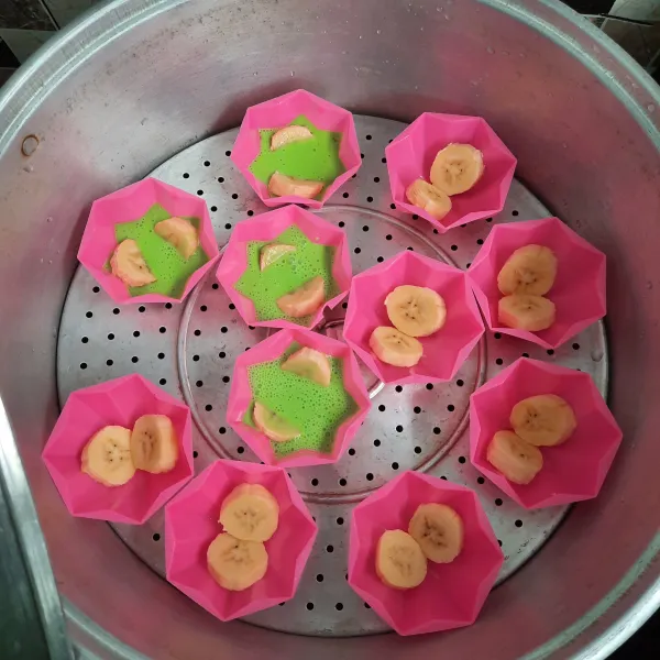 Olesi cetakan dengan minyak goreng. Letakkan potongan pisang.