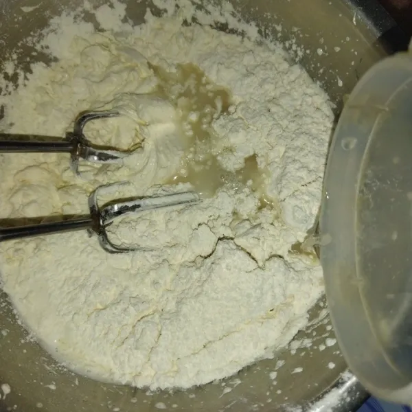 Lalu masukkan tepung terigu bergantian dengan air kelapa.