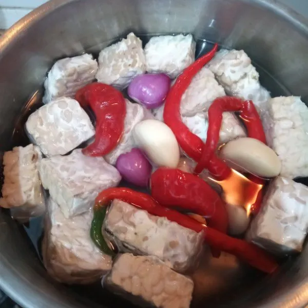 Rebus tempe bersama bawang merah, bawang putih, kencur, dan cabai merah hingga matang bersama 500 ml air.