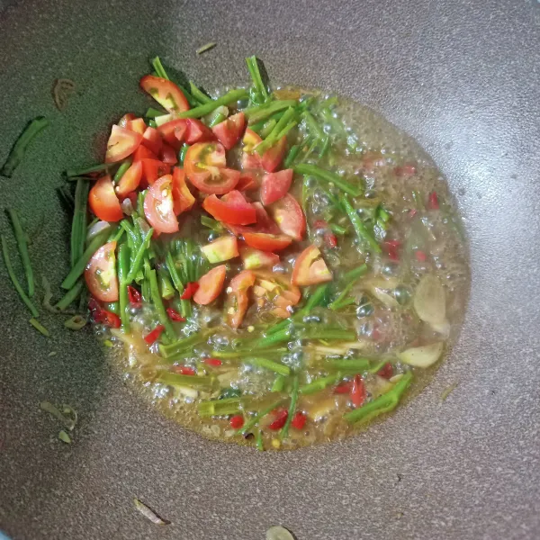 Masukkan kangkung bagian batang dan tomat, lalu aduk hingga rata. Masukkan air, masak hingga batang kangkung matang.