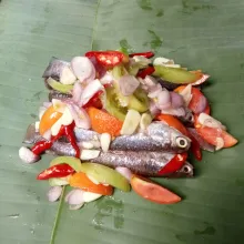 Letakkan ikan beserta bumbu di atas daun pisang, lalu bungkus dan sematkan kedua ujungnya dengan lidi.