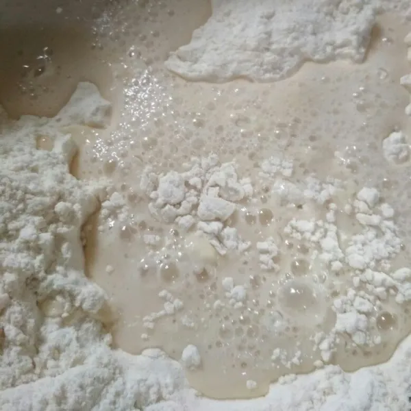 Dalam bowl campur tepung terigu dan susu bubuk aduk rata tambahkan adonan biang aduk hingga tercampur rata dengan spatula