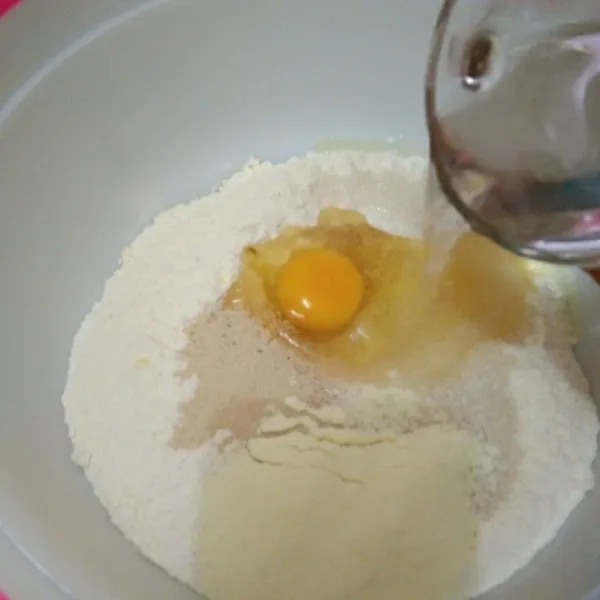 Dalam wadah campur tepung terigu, telur ayam, ragi instan, air, gula pasir, dan susu bubuk hingga rata.