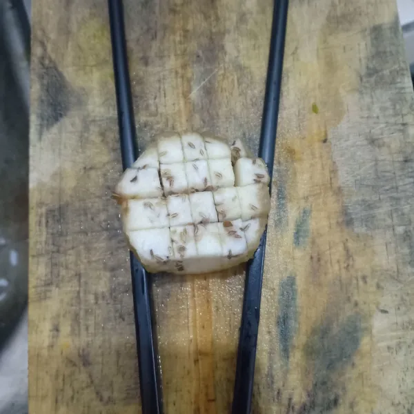 Potong-potong terong, alasi dengan sumpit agar tidak terputus bawahnya.