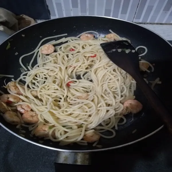 Masukkan spaghetti, beri 3 sdm air (dari sisa rebusan spaghetti). Lalu tambahkan kaldu jamur dan irisan daun bawang. Lalu tambahkan keju parmesan, setelah itu matikan api.