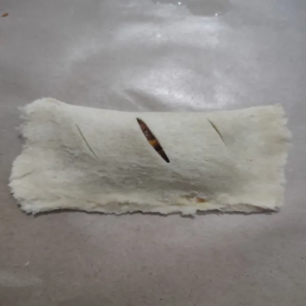 Pisahkan kuning telur dengan putihnya, olesi pinggiran roti dengan putih telur, lalu lipat dan kunci pinggirnya dengan garpu. Kemudian buat sayatan di bagian atasnya.
