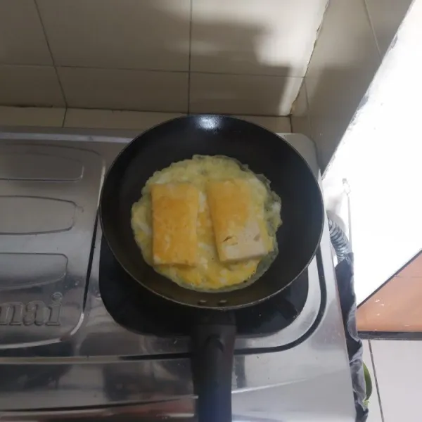 Buat telur dadar lalu taruh roti di atasnya.