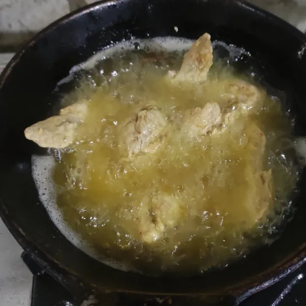 Goreng ayam dalam minyak panas hingga matang dan berwarna coklat keemasan.