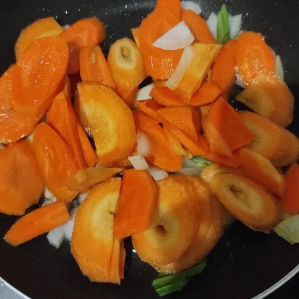 Masukkan daun bawang dan wortel. Tumis sampai layu.