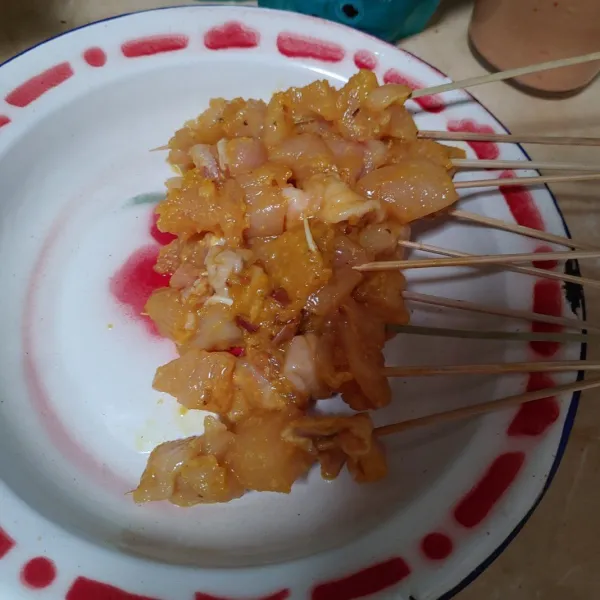Tusuk daging ayam dengan tusukan sate.