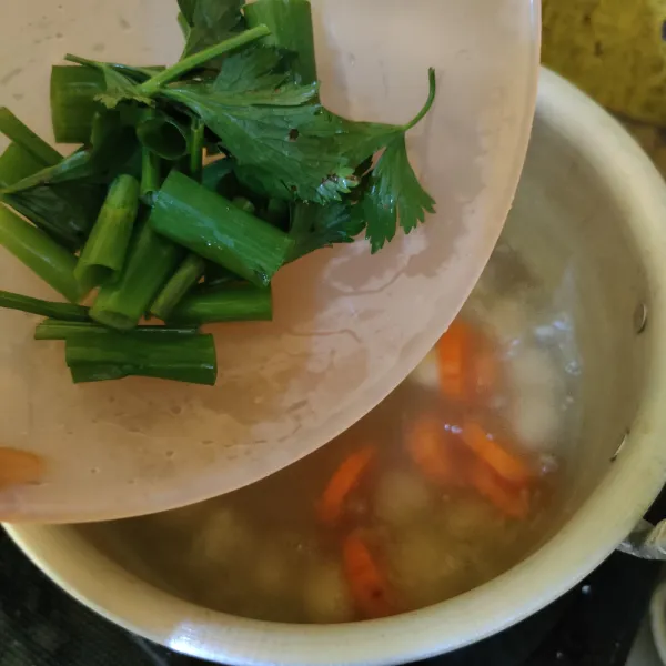 Masukkan daun bawang dan daun seledri, lalu aduk rata. Masak hingga mendidih kembali, lalu matikan api.