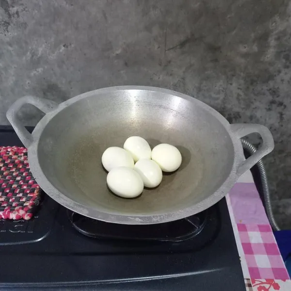Masukkan telur rebus yang sudah dikupas ke dalam wajan.