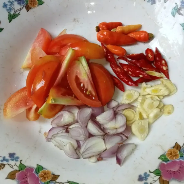 Potong-potong tomat dan cabai, iris tipis bawang merah dan bawang putih.