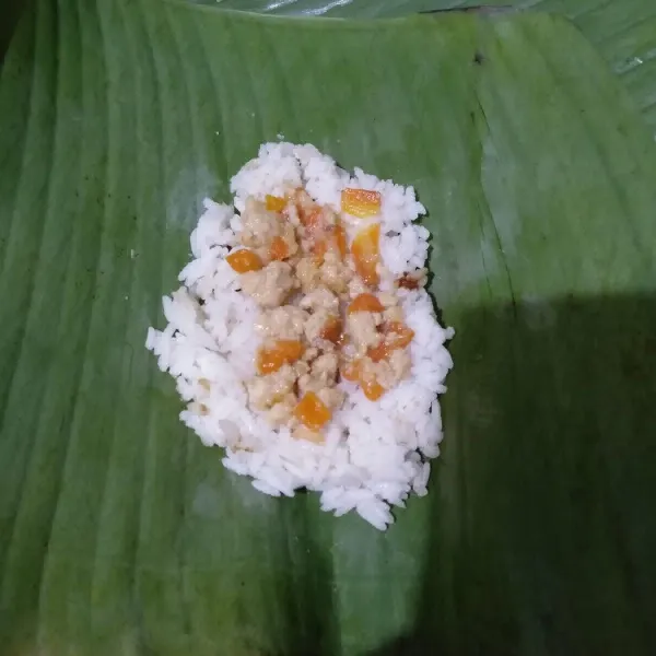 Ambil 2 lembar daun pisang, ratakan nasi dan beri bahan isi secukupnya. Bungkus seperti lemper, lalu semat dengan lidi.
