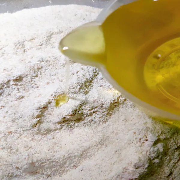 Tuang campuran tepung dengan minyak sedikit demi sedikit sambil di aduk.