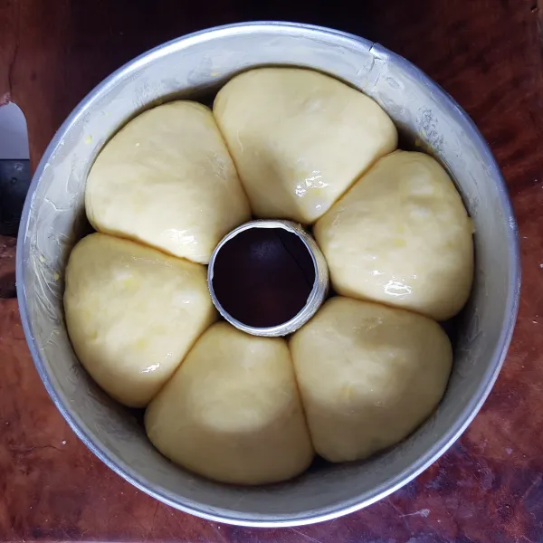 Setelah mengembang 2 kali lipat, oles permukaan atas adonan roti dengan campuran kuning telur dan susu cair.