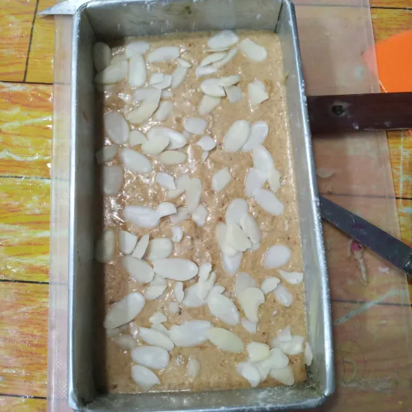 Tuang ke dalam loyang yang sudah dioles margarin lalu taburkan almond slices di atasnya.