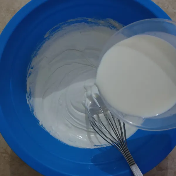 Masukkan susu cair sedikit demi sedikit sambil diaduk menggunakan whisker.