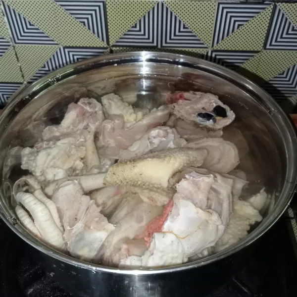 Potong-potong ayam dan cuci bersih, lalu rebus dengan air di panci.