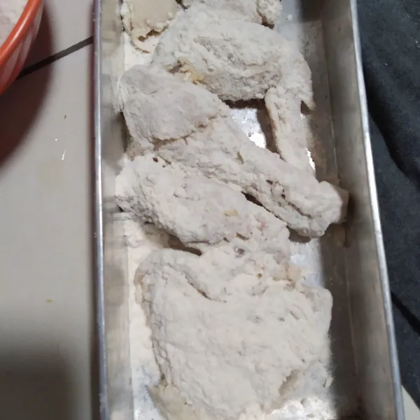 Masukkan ayam ke dalam tepung bumbu serbaguna, aduk rata sambil ditekan-tekan agar tepung menempel pada daging.