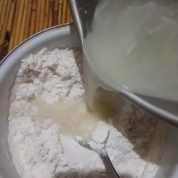 Rebus air bersama bawang putih sampai mendidih, kemudian langsung tuang ke dalam campuran tepung.