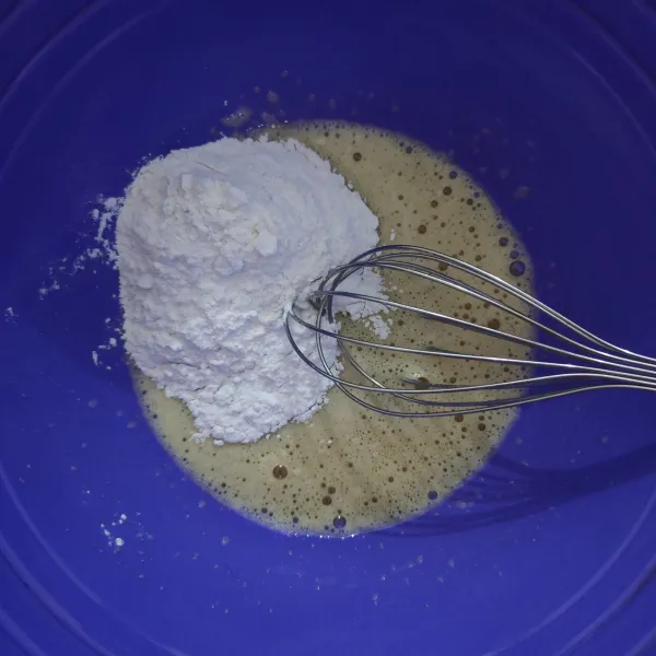 Masukkan campuran tepung ke dalam kocokan telur, sambil diaduk menggunakan tangan.