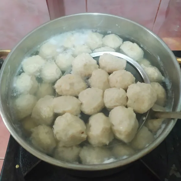 Cetak bakso dengan tangan atau pakai 2 sendok, masukkan ke dalam panci berisi air panas. Setelah semua selesai dicetak, nyalakan kompor dan tunggu bakso mengapung. Tiriskan.